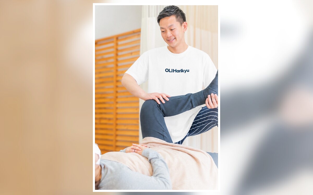 白い施術着で患者様の脚をストレッチする院長と施術シーン全体